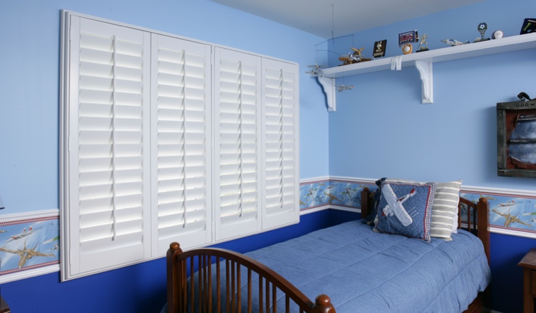Large plantation shutters covering window in blue kids bedroom in Hartford 